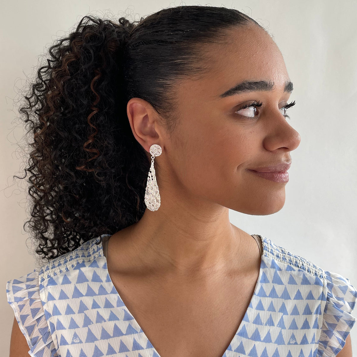 Teardrop lace earrings dipped in sterling silver on model.