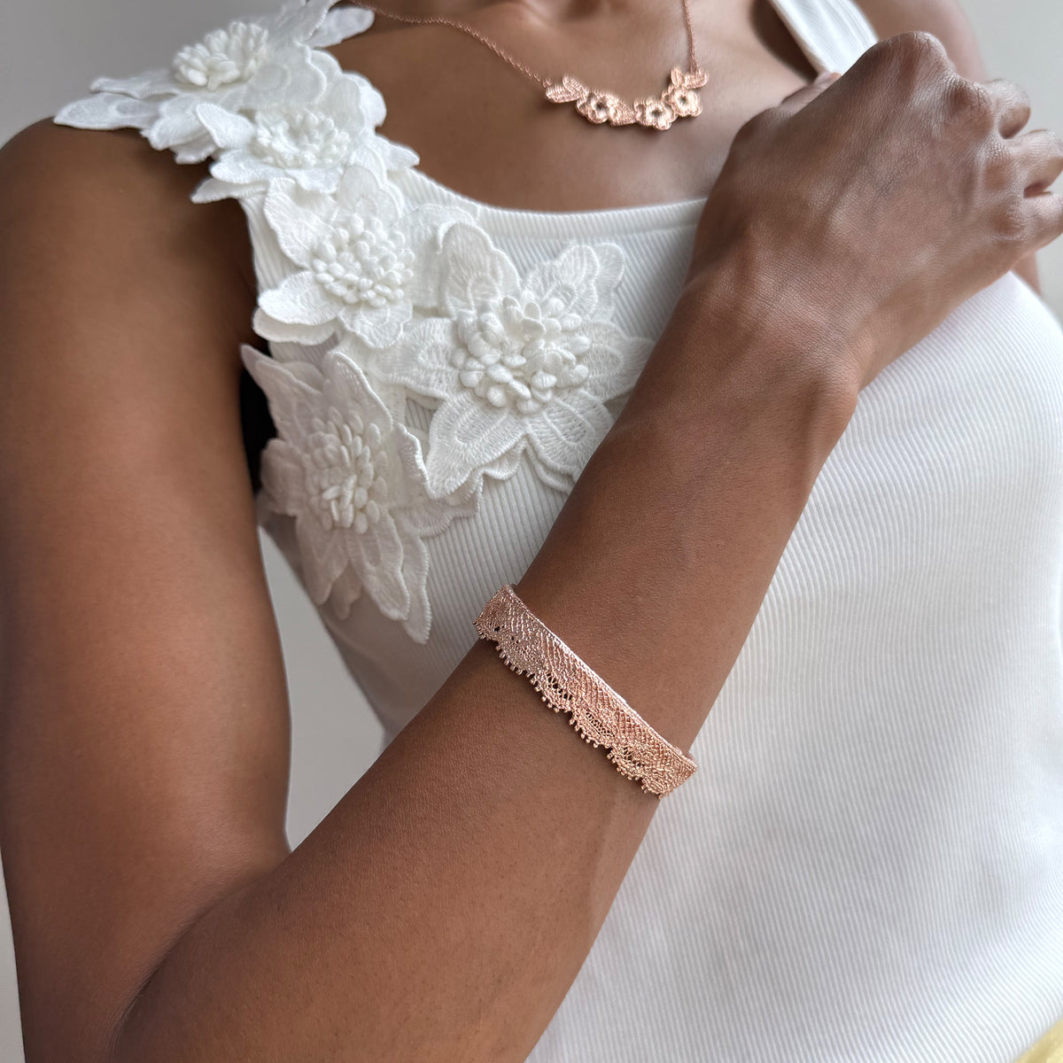Model wearing a lace bangle bracelet in dipped rose gold.