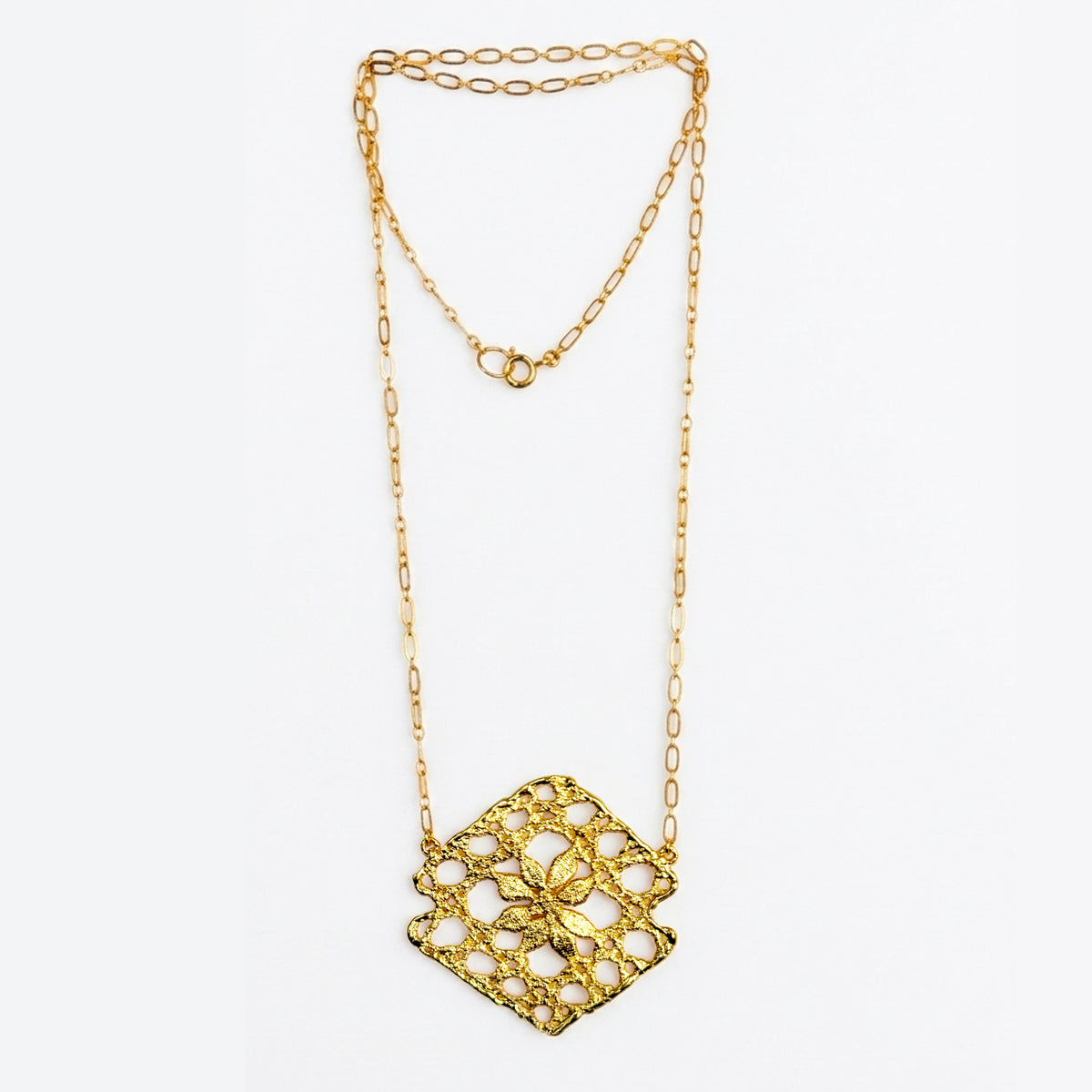 Lace pendant necklace in 24k gold on white background.