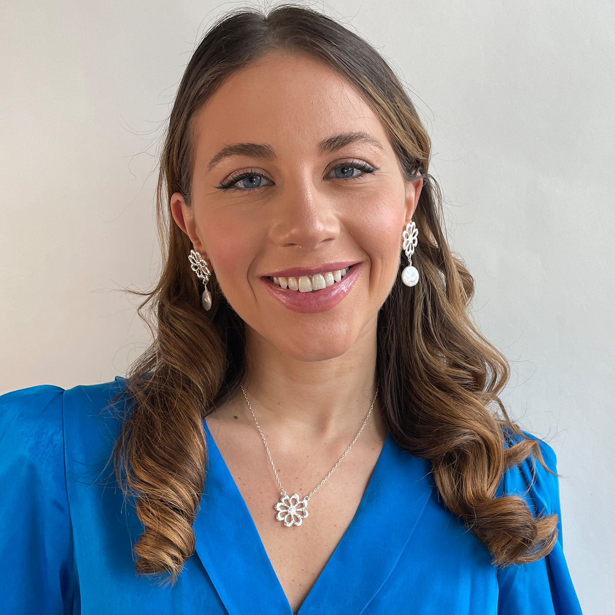Model wearing silver floral lace earrings with baroque coin pearls and a silver floral lace necklace.