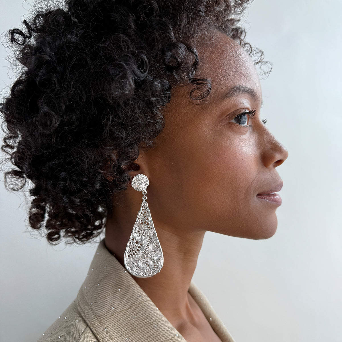 Model wearing lace tear drop earrings dipped in sterling silver, feather light. 