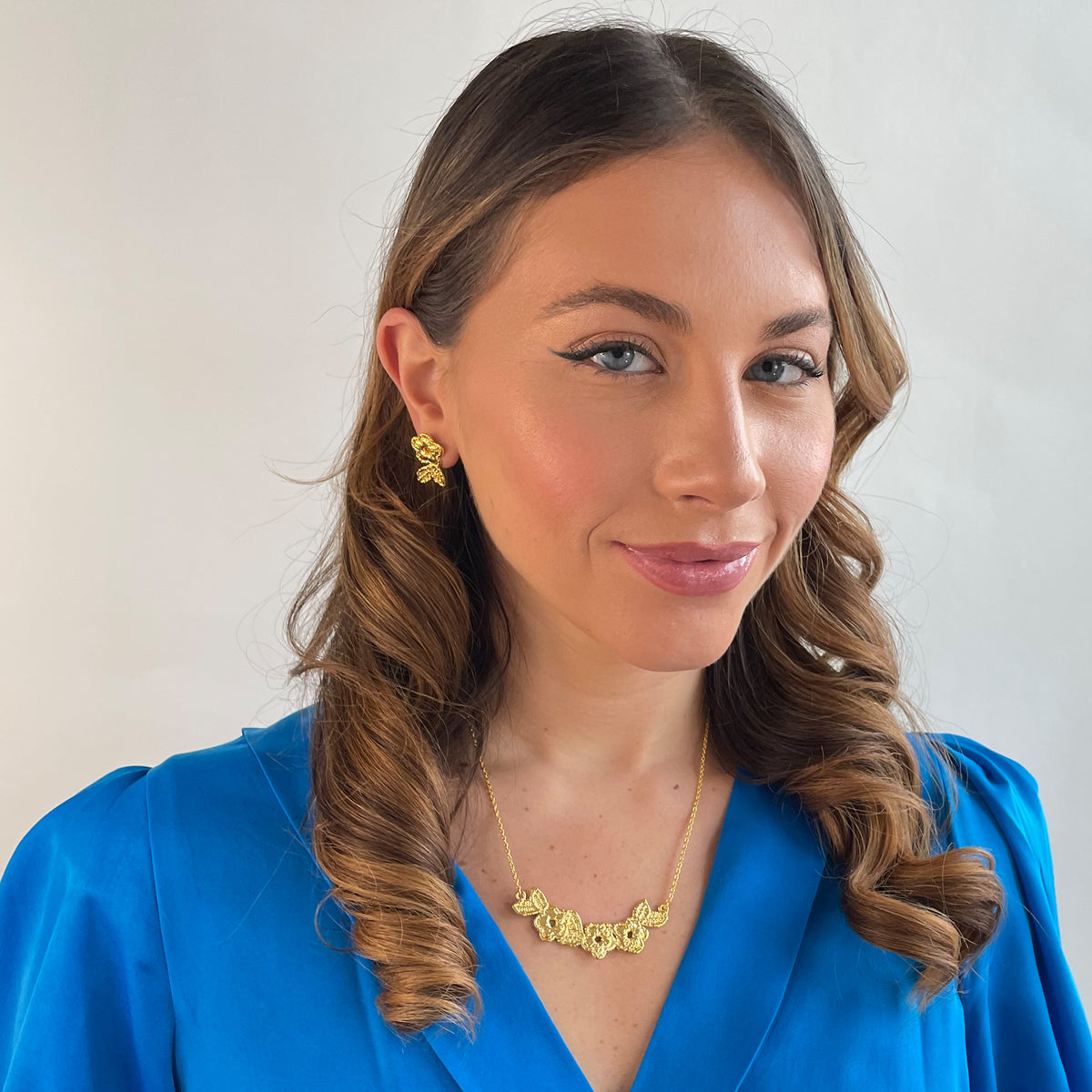 Ella lace earrings and Ellinor lace necklace in 24k gold on a model.