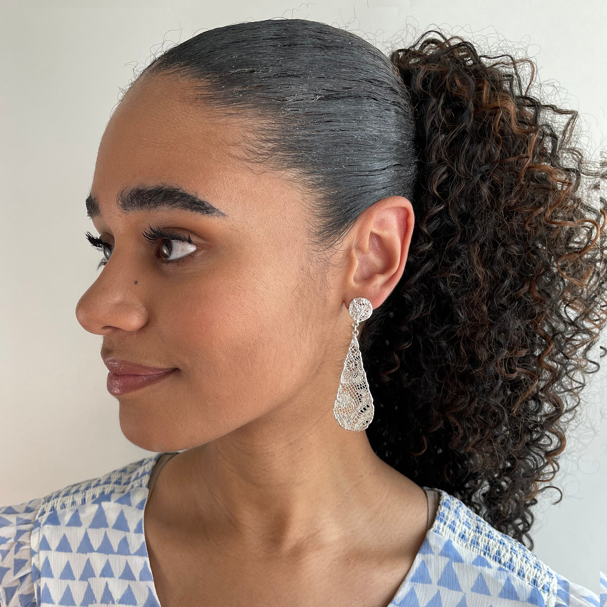 Teardrop lace earrings dipped in sterling silver on model.