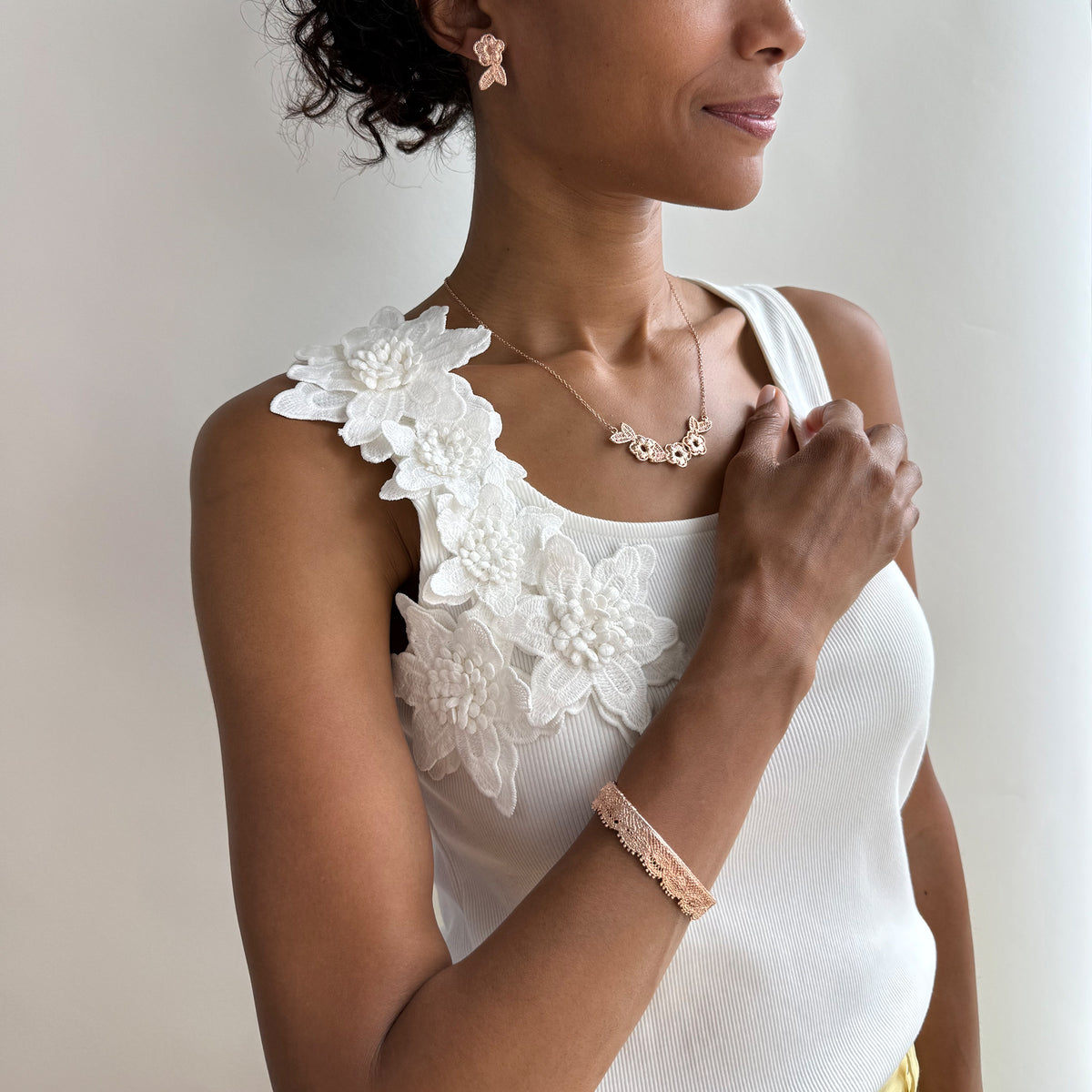 Model wearing a lace bangle bracelet in dipped rose gold.
