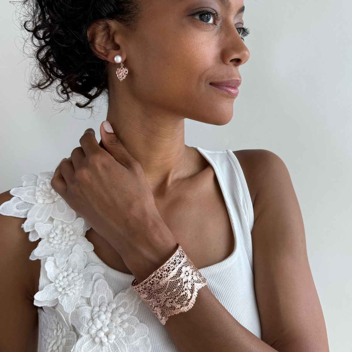 Model wearing intricate lace cuff bracelet in rose gold.