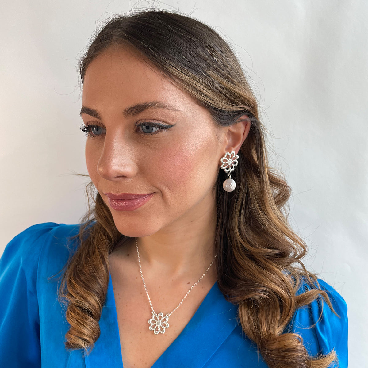 Model wearing silver floral lace earrings with baroque coin pearls and a silver floral lace necklace.
