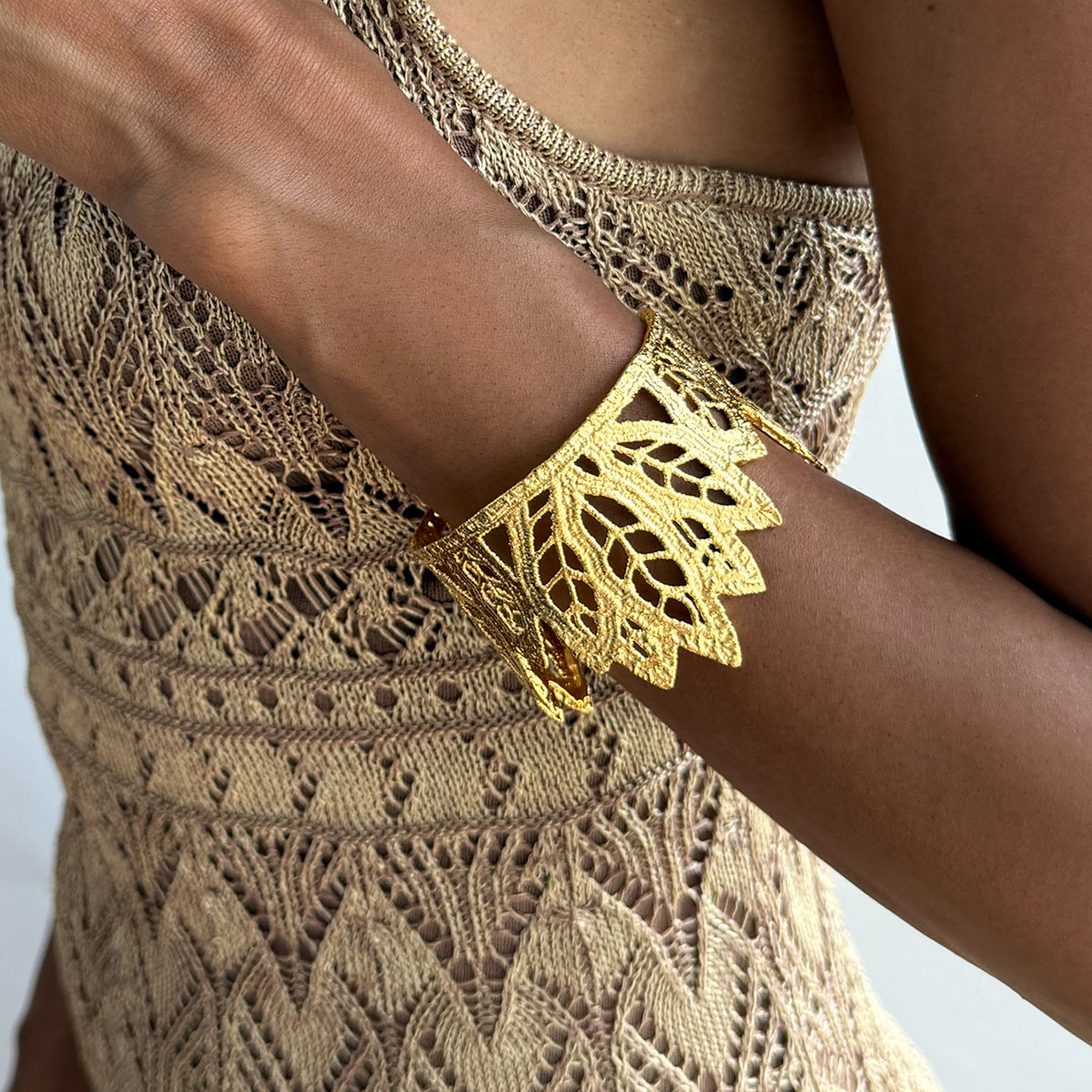A model wearing a lace leaf bracelet in dipped 24k gold.