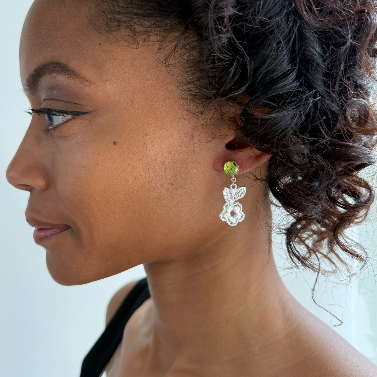 Model wearing peridot earrings with lace flowers in sterling silver.