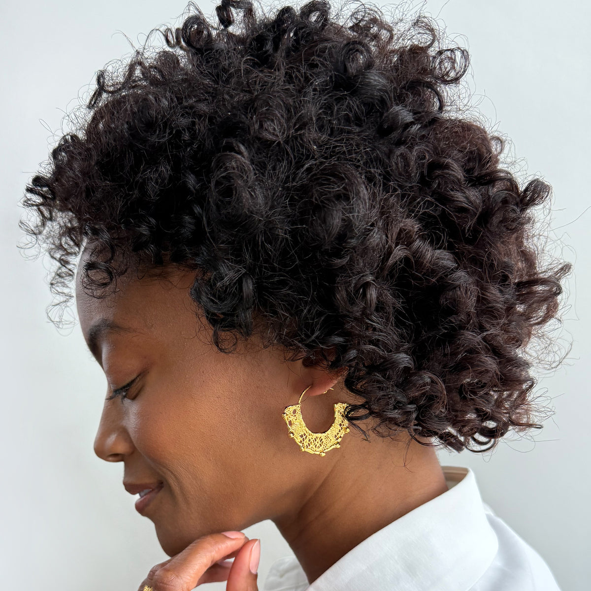 Model wearing Violette 24k gold hoop earrings with intricate designs.