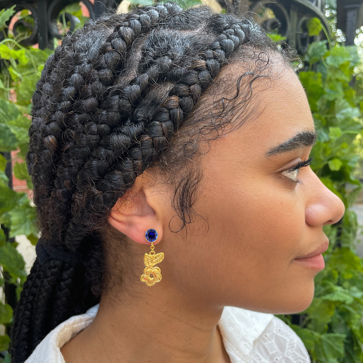 Flower lace earrings in 24k gold with blue sapphires worn by model.