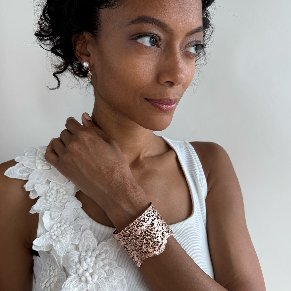 Model wearing intricate lace cuff bracelet in rose gold.