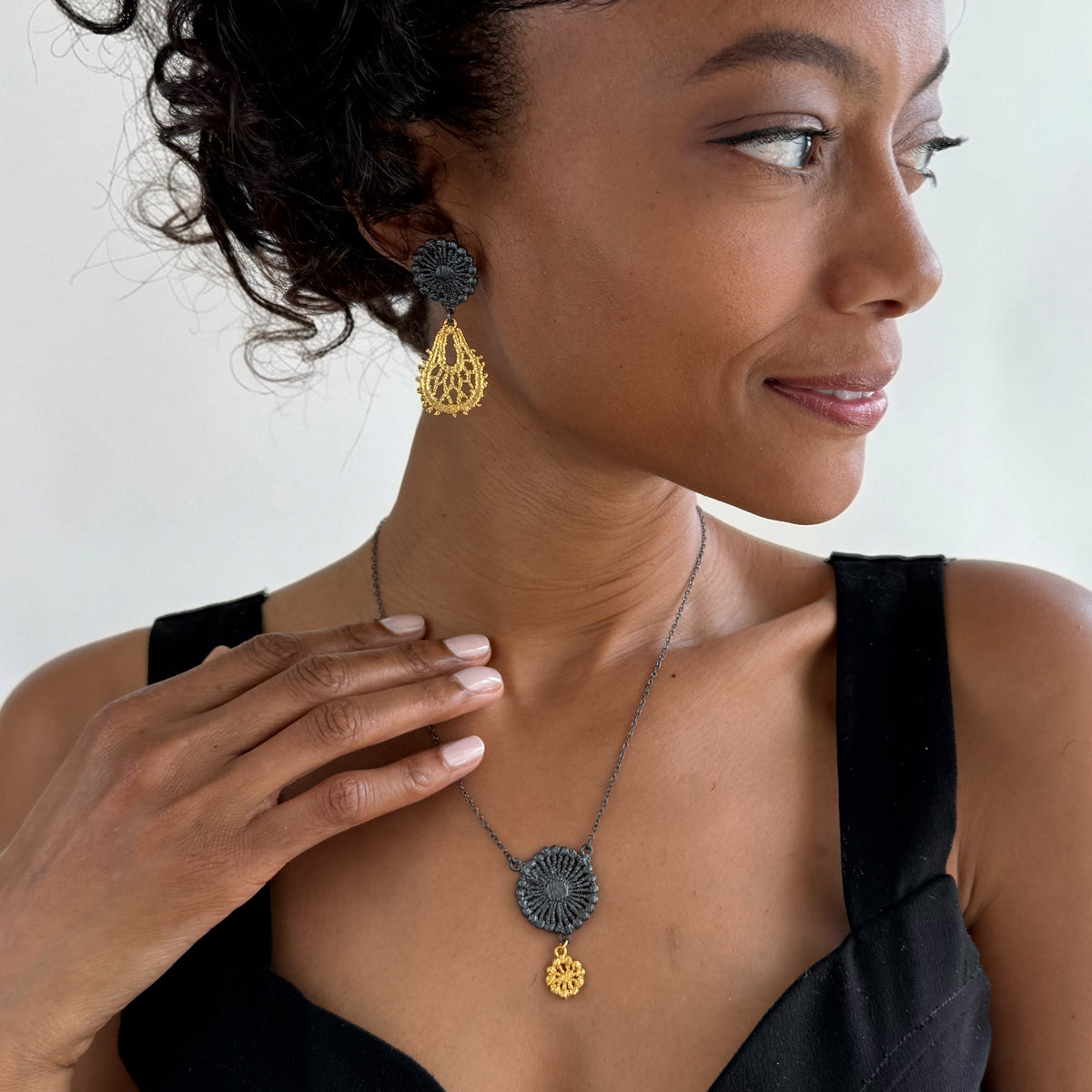 Model wearing the Flora lace earrings in 24k gold and oxidized black sterling silver.