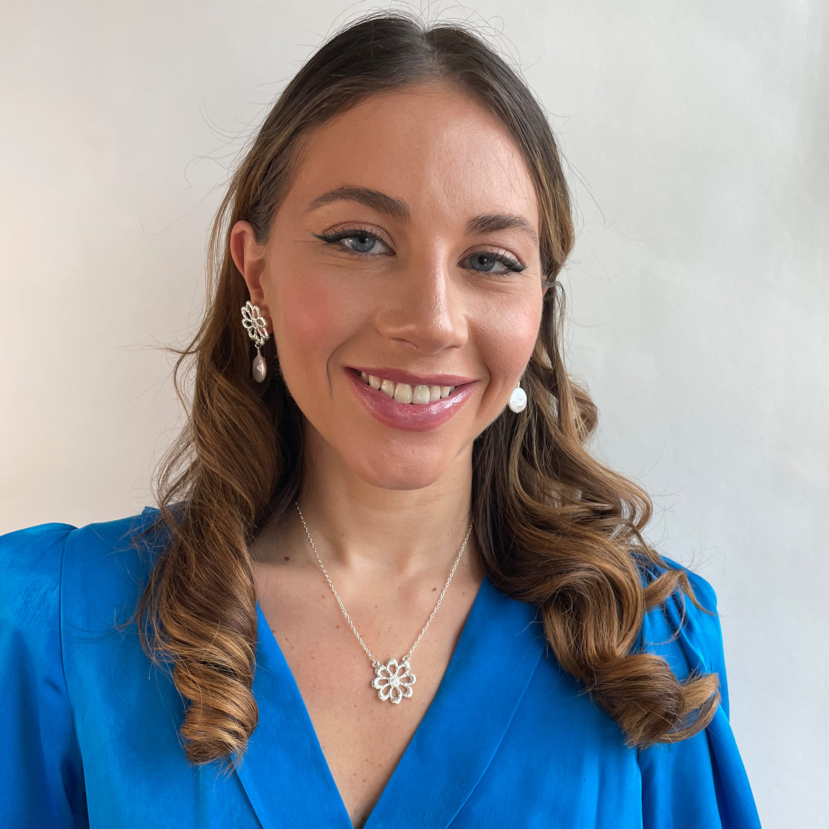 Model wearing silver floral lace earrings with baroque coin pearls and a silver floral lace necklace.