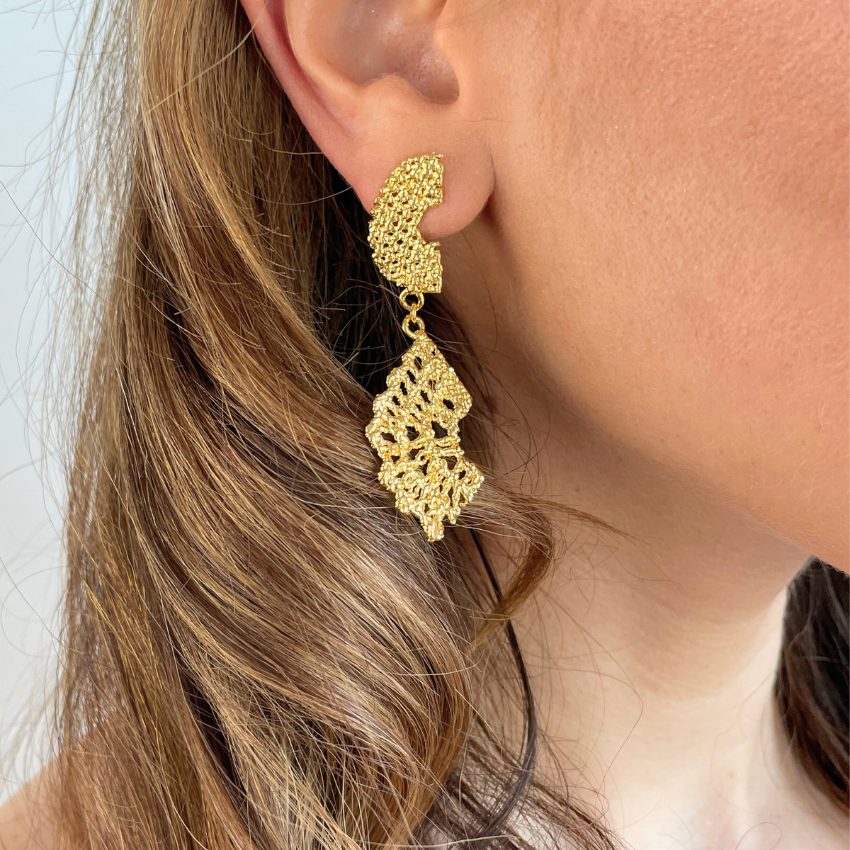 Model wearing dangle lace earrings dipped in 24k gold.
