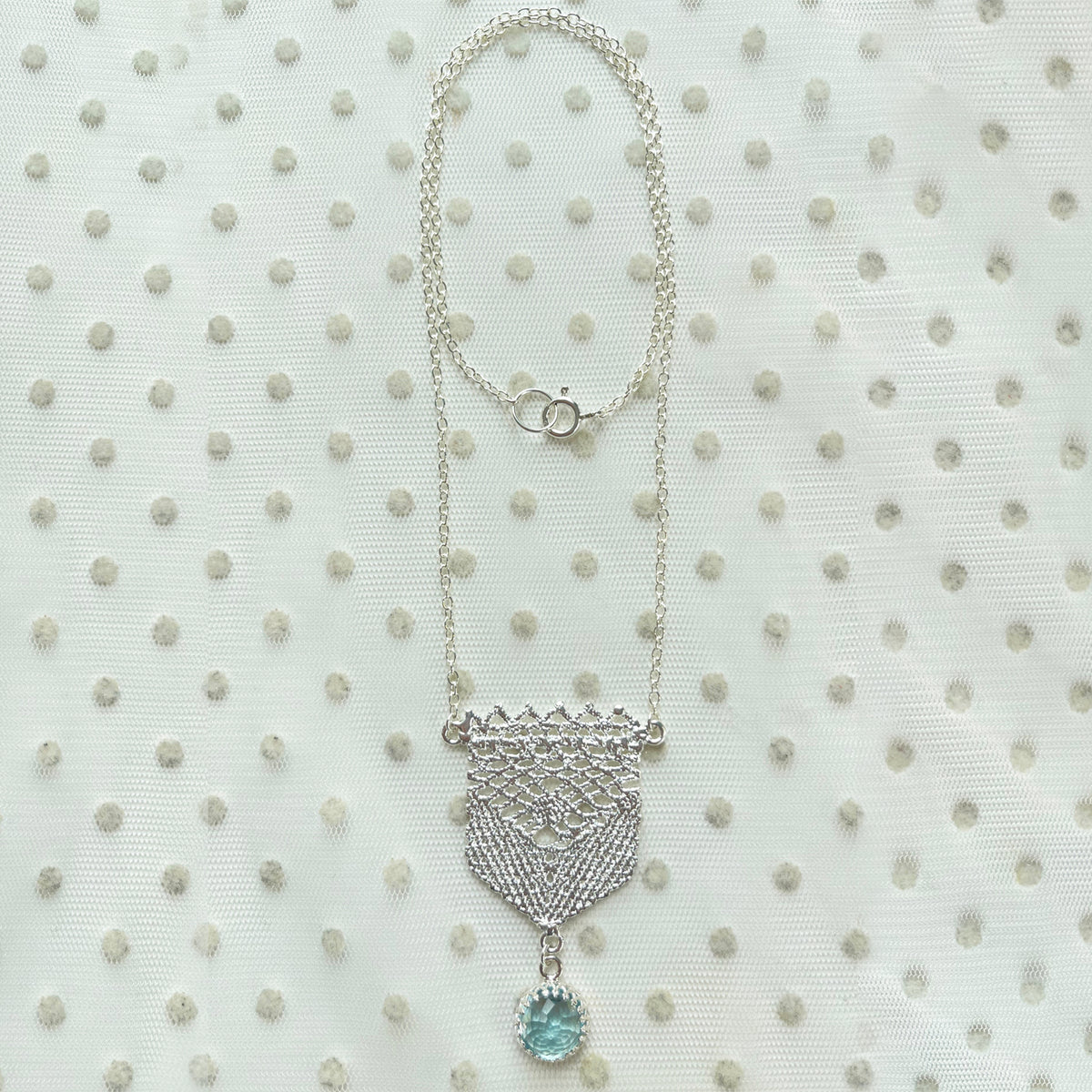 Lace pendant in silver with a faceted Aquamarine stone.