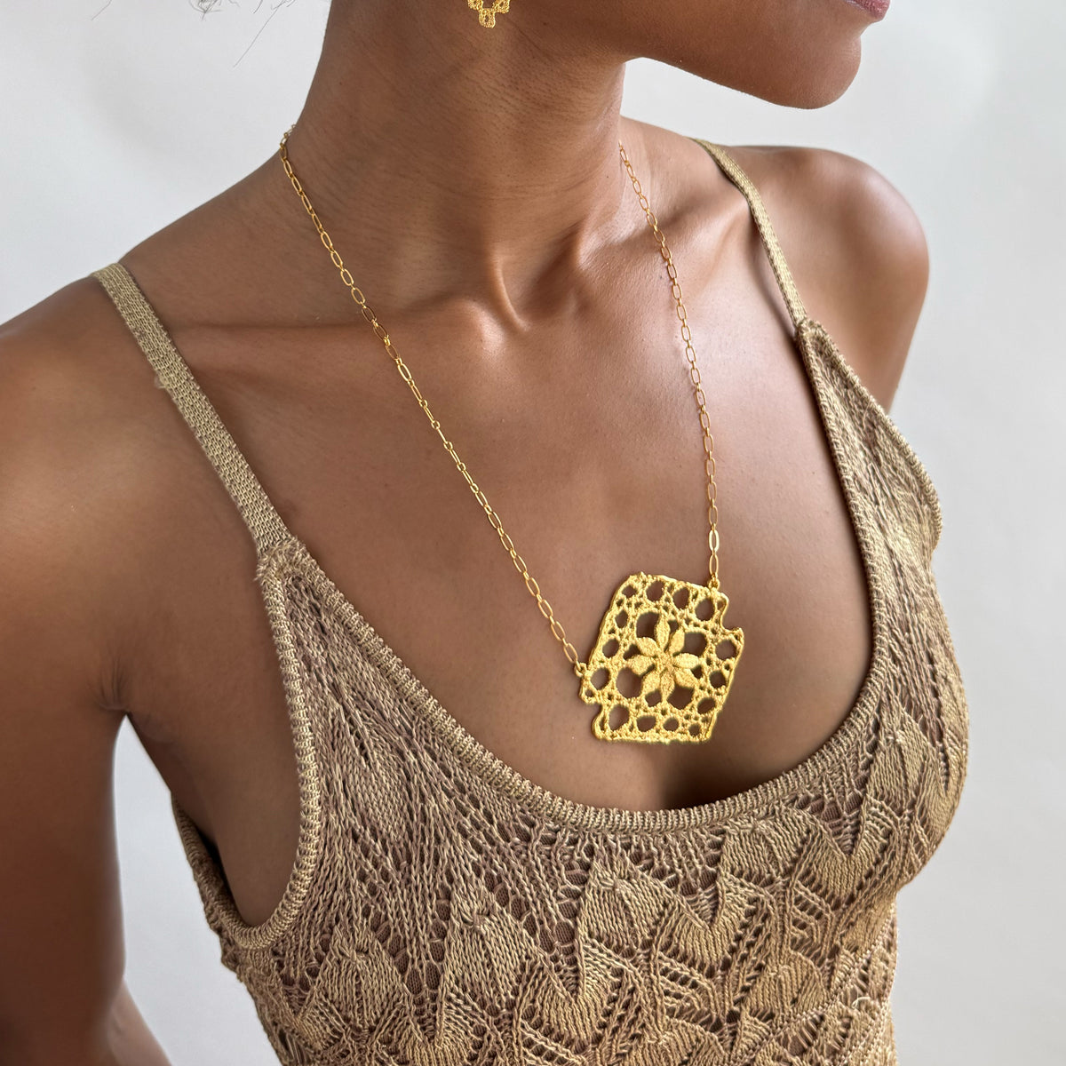 Model wearing lace pendant necklace in 24k gold.