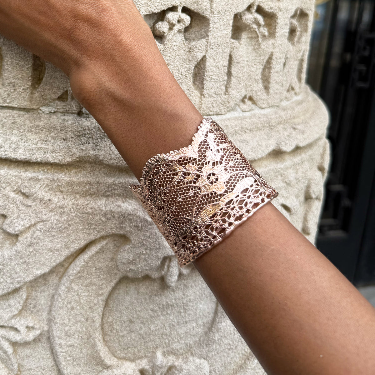 Model wearing intricate lace cuff bracelet in rose gold.