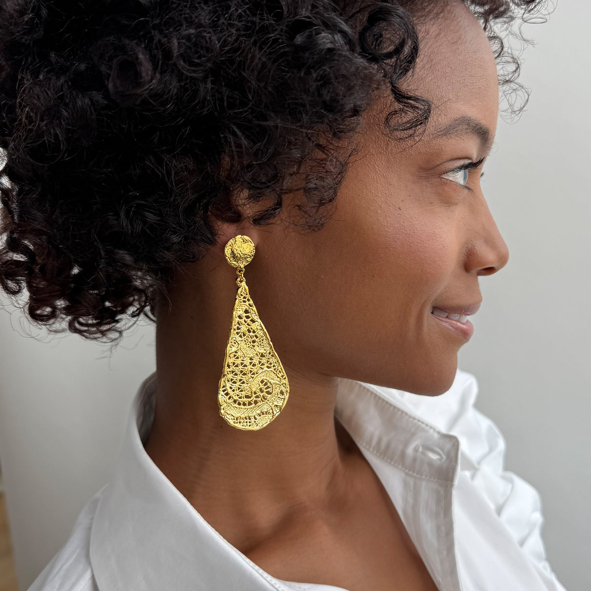 Model wearing lace tear drop earrings dipped in 24k gold, feather light. 