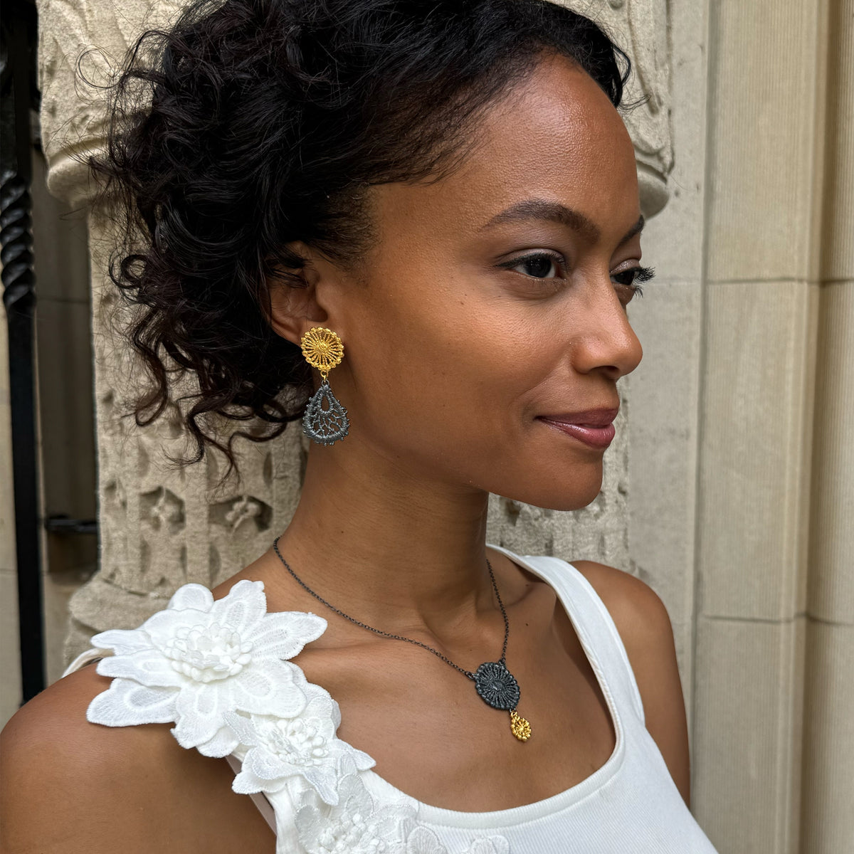 Model wearing the Flora lace earrings in 24k gold and oxidized black sterling silver.