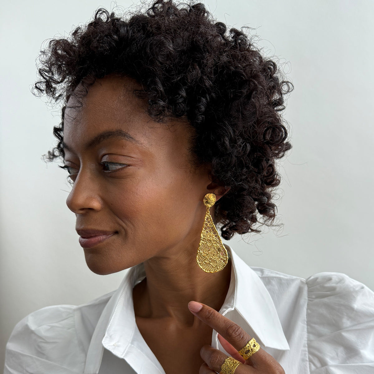 Model wearing lace tear drop earrings dipped in 24k gold, feather light. 