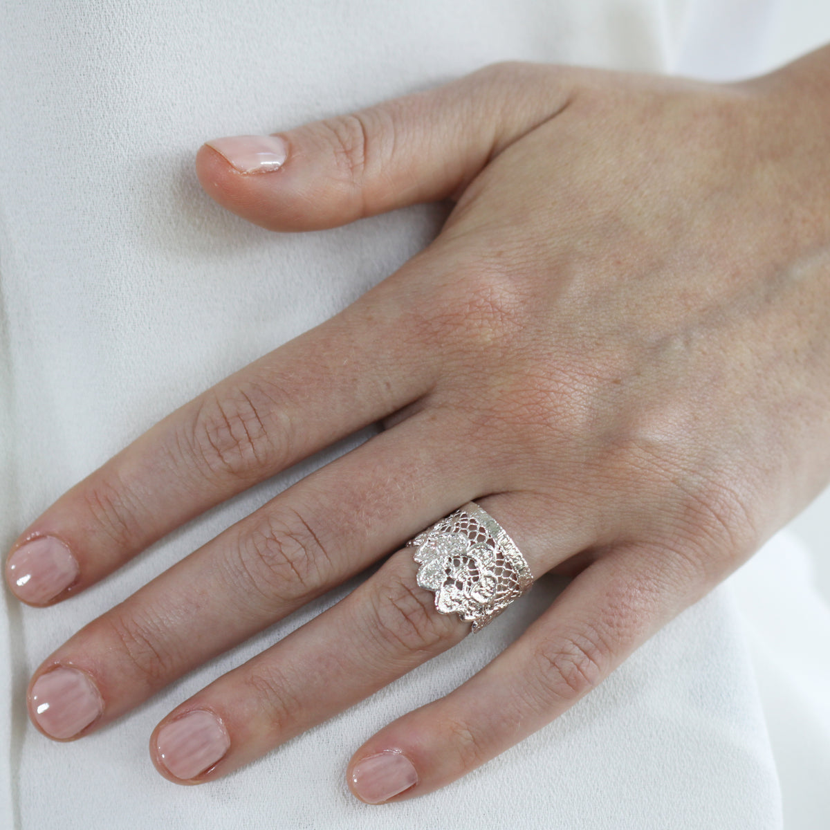 A model wearing a sterling silver ring featuring an intricate embroidered net lace design from the 1940s.