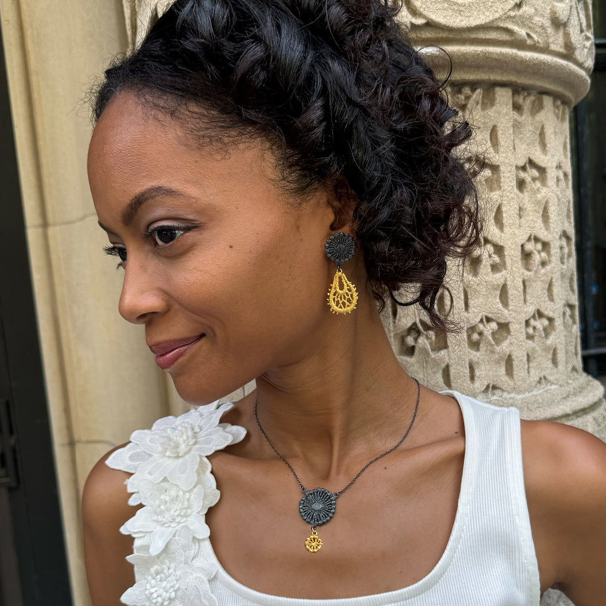 Model wearing the Flora lace earrings in 24k gold and oxidized black sterling silver.