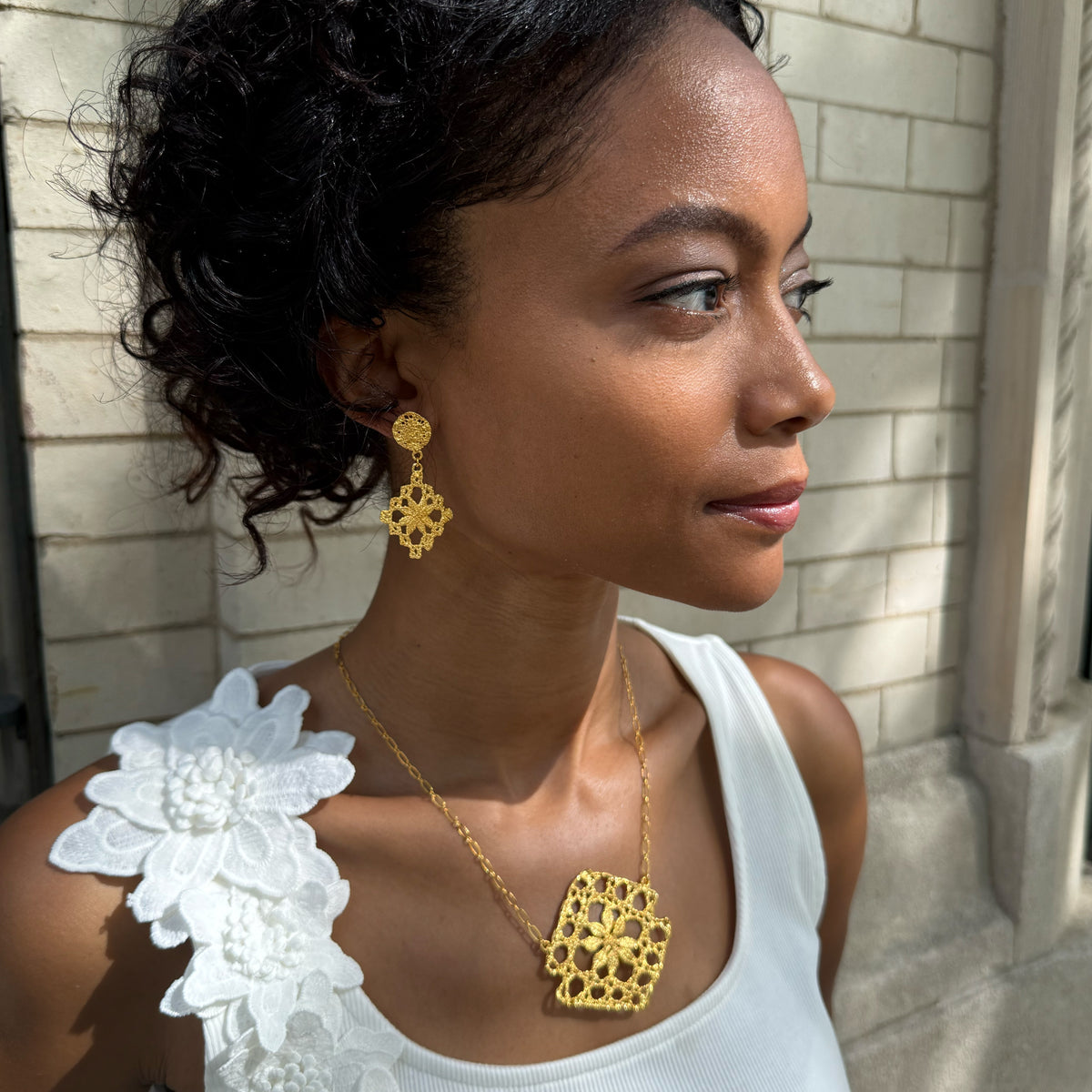 Model wearing chandelier lace earrings and lace pendant necklace, both in 24k gold.