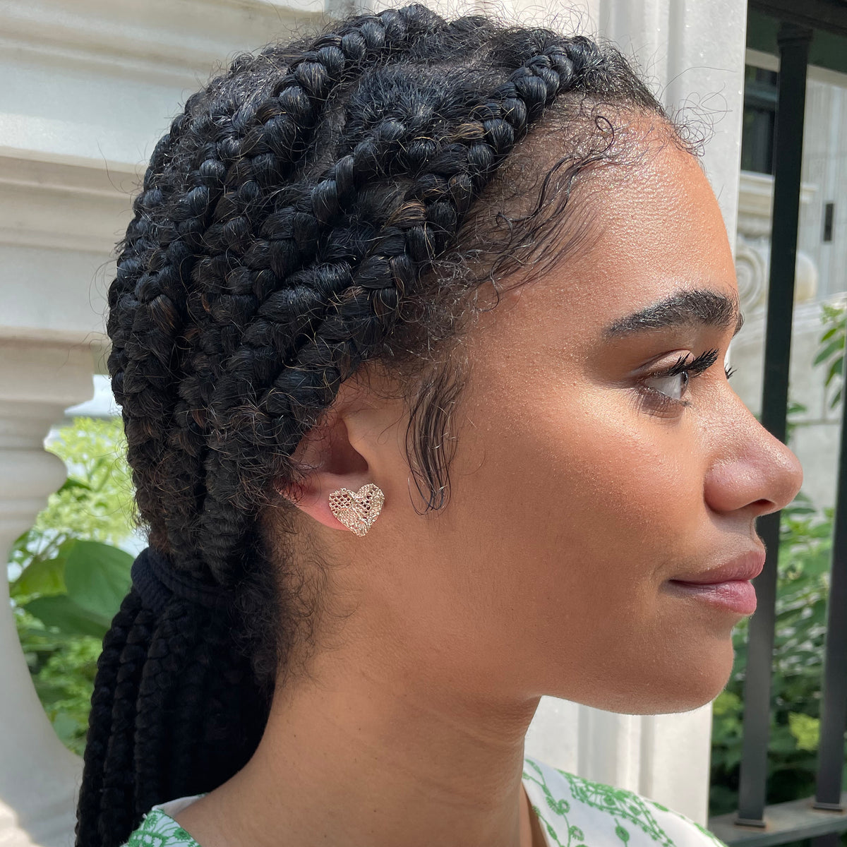 Lace heart stud earrings in rose gold worn by model.