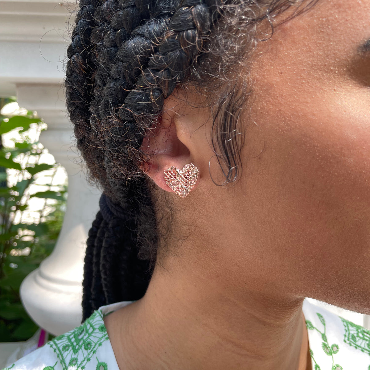 Lace heart stud earrings in rose gold worn by model.