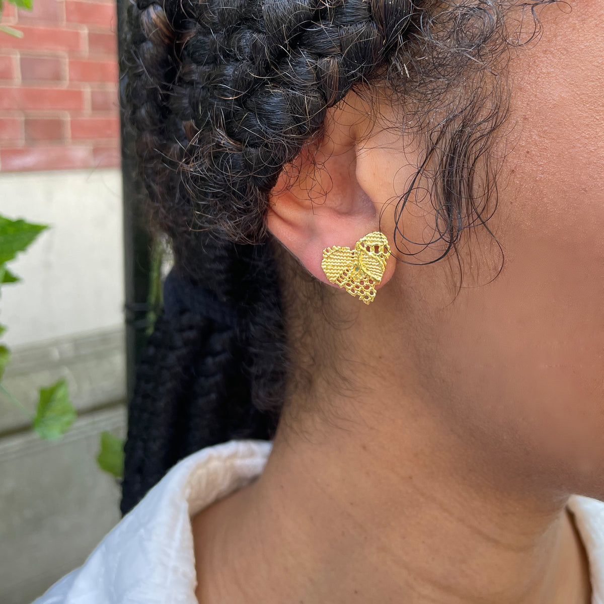 Lace heart stud earrings in 24k gold worn by model.