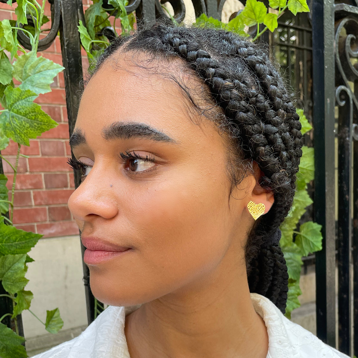 Lace heart stud earrings in 24k gold worn by model.