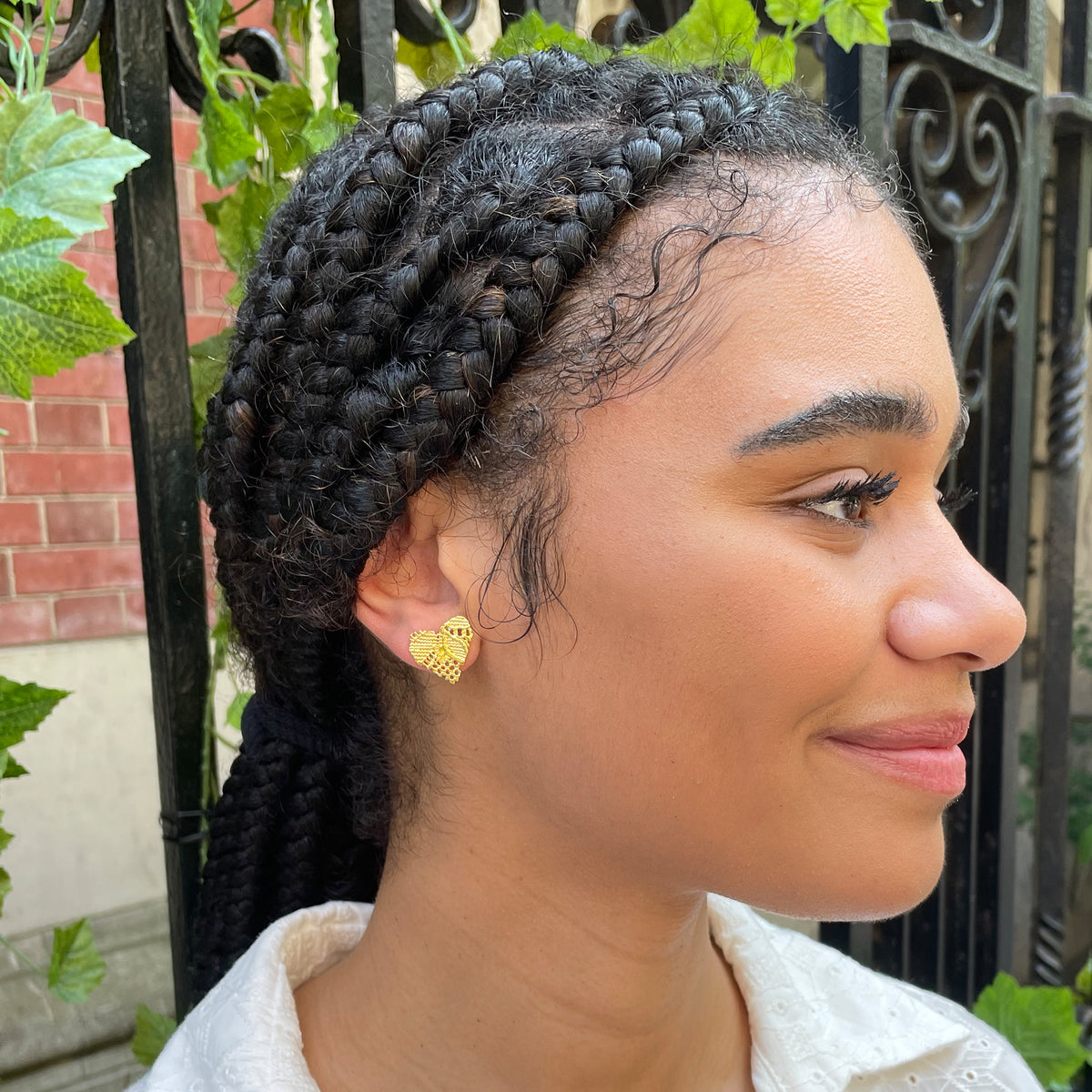 Lace heart stud earrings in 24k gold worn by model.