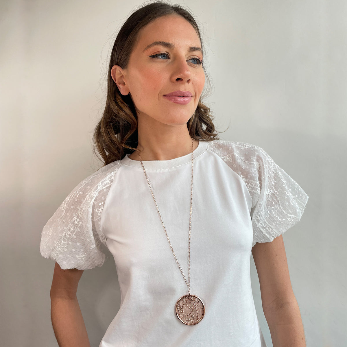 Cecilia circular lace pendant necklace in rose gold worn by a model.