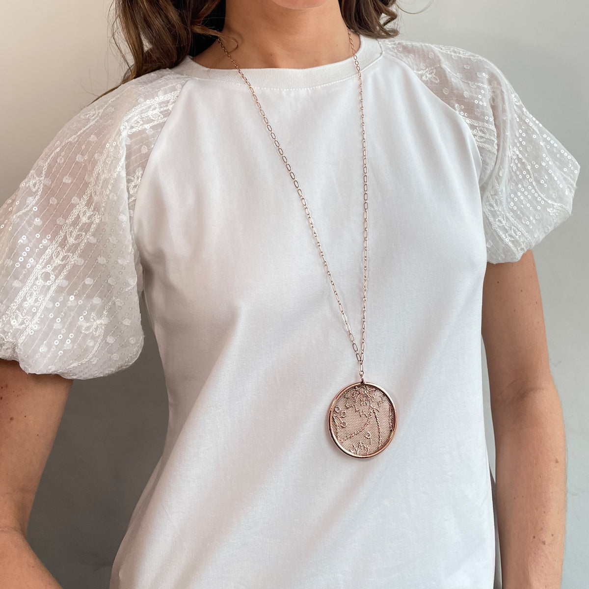 Cecilia circular lace pendant necklace in rose gold worn by a model.
