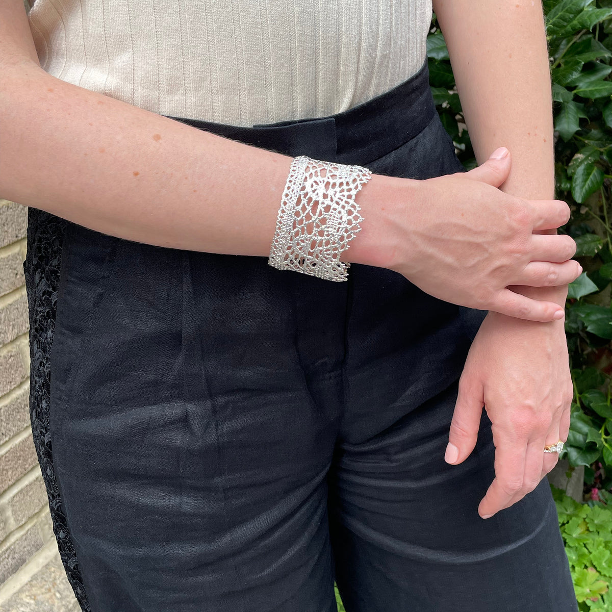 Intricate and exquisite lace cuff bracelet in sterling silver worn by a model.