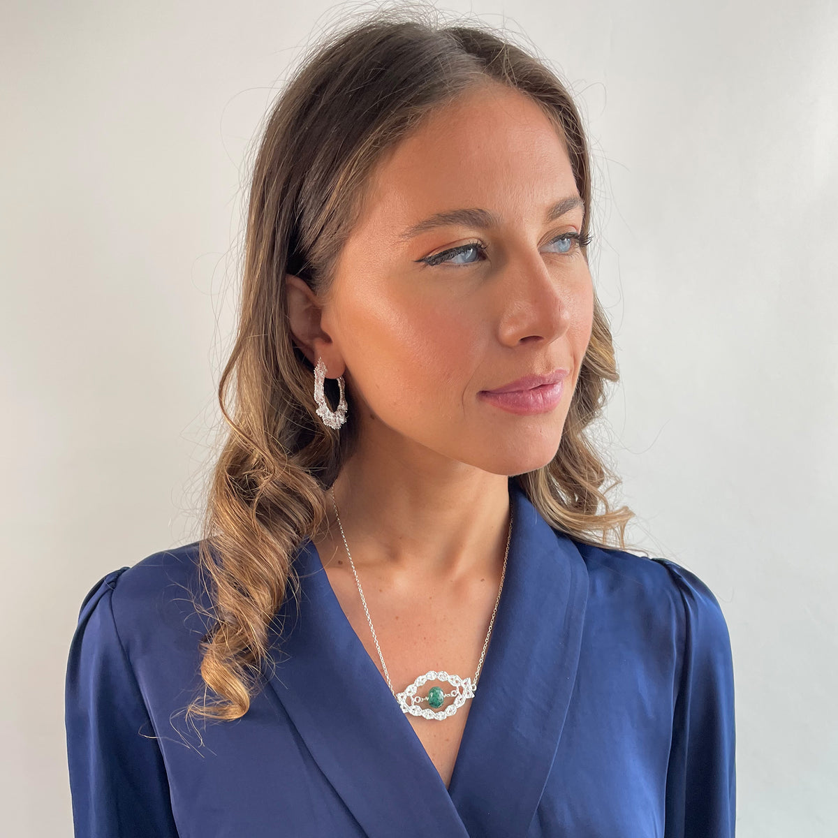 Chloé silver lace pendant with an Emerald centerpiece on a model.