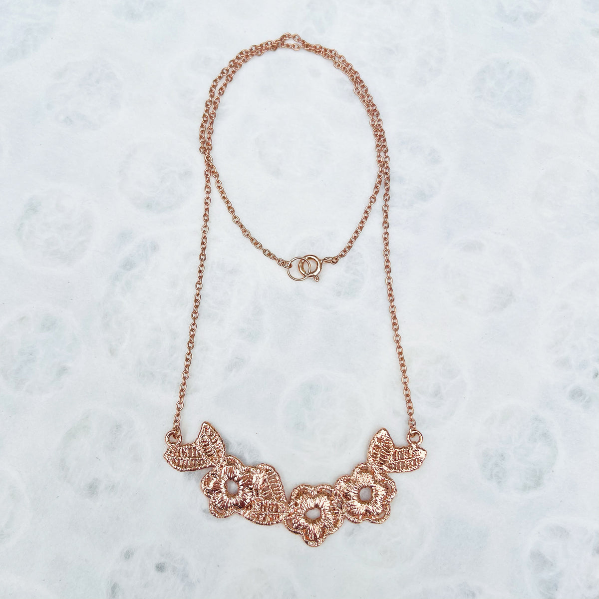 Lace flower garland necklace in rose gold.
