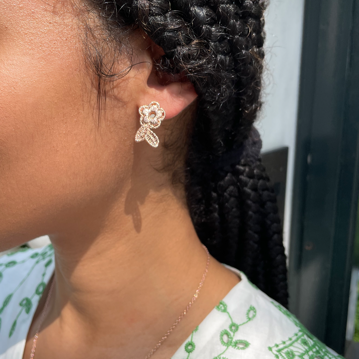 Flower lace stud earrings in rose gold worn by a model.