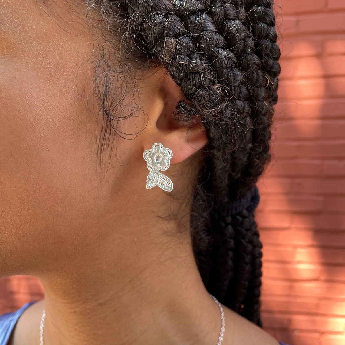 Flower lace stud earrings in sterling silver worn by a model.