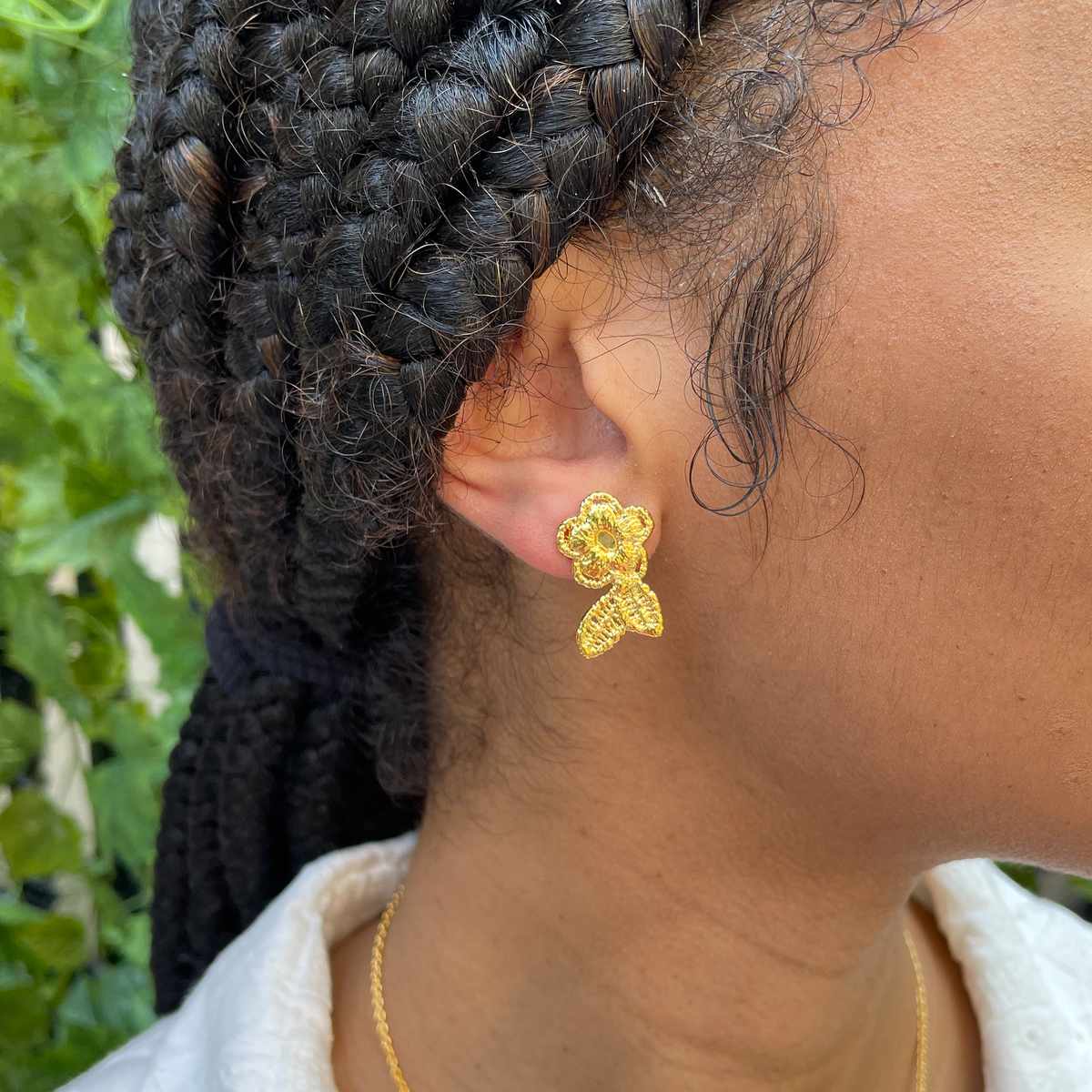 Flower lace stud earrings in 24k gold worn by model.