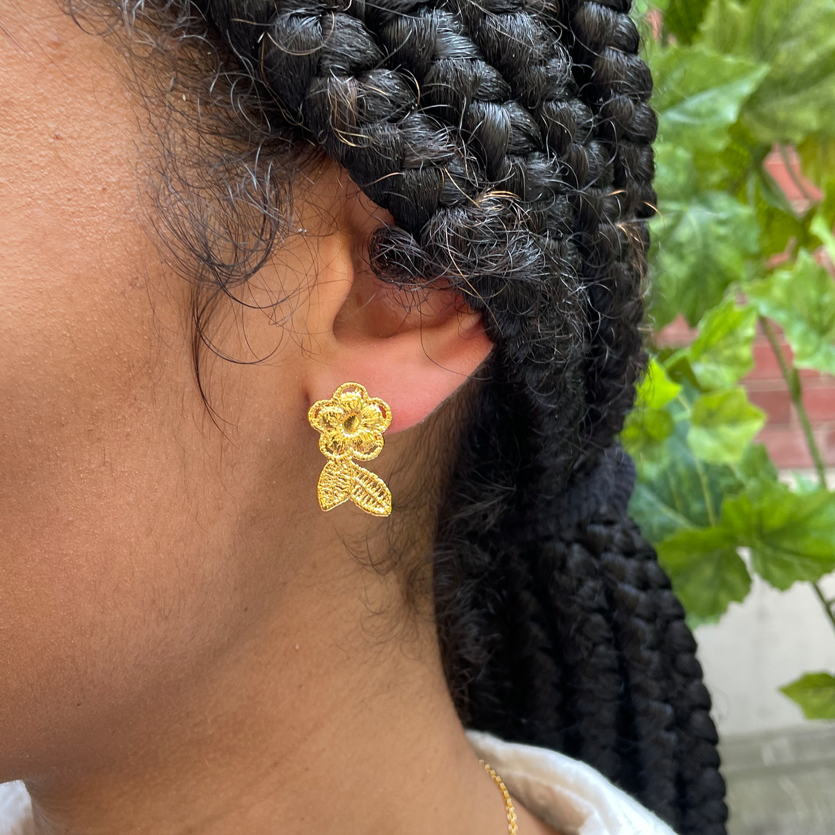 Flower lace stud earrings in 24k gold worn by model.