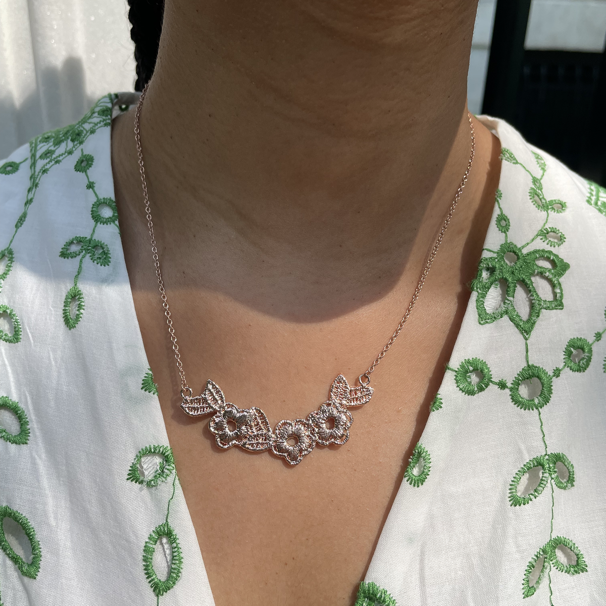 Lace flower garland necklace in rose gold worn by a model.