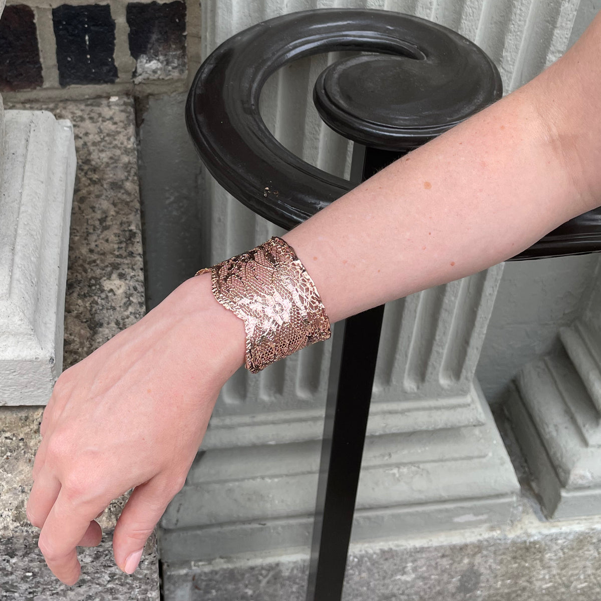 Intricate lace cuff bracelet in rose gold worn by model.