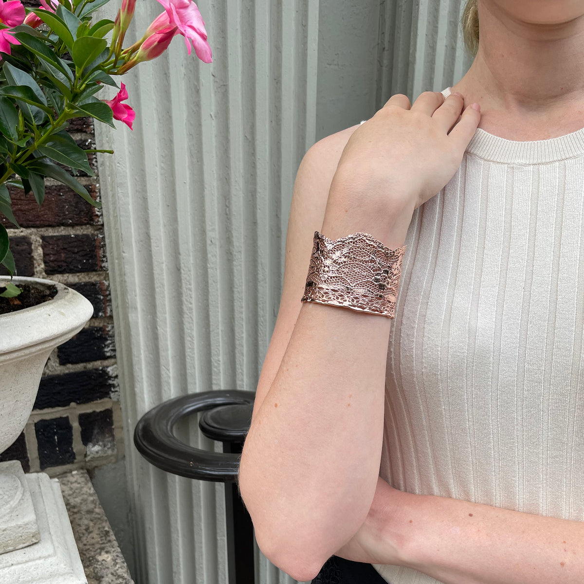 Intricate lace cuff bracelet in rose gold worn by model.