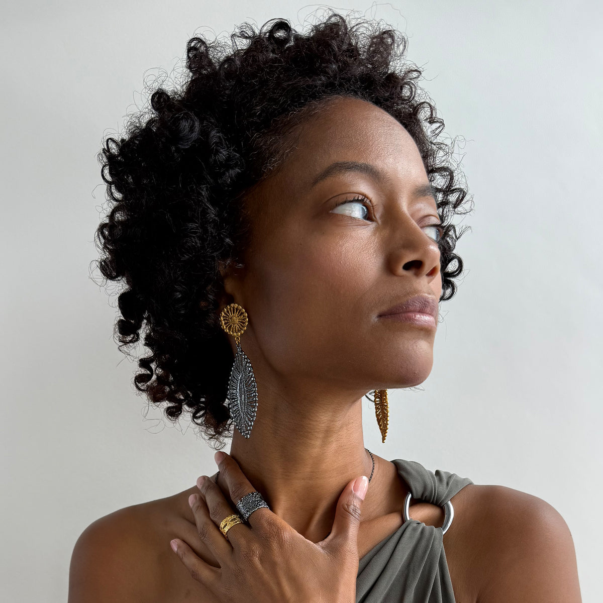 A model wearing a pair of leaf shaped 24k gold and black oxidized sterling silver earrings.