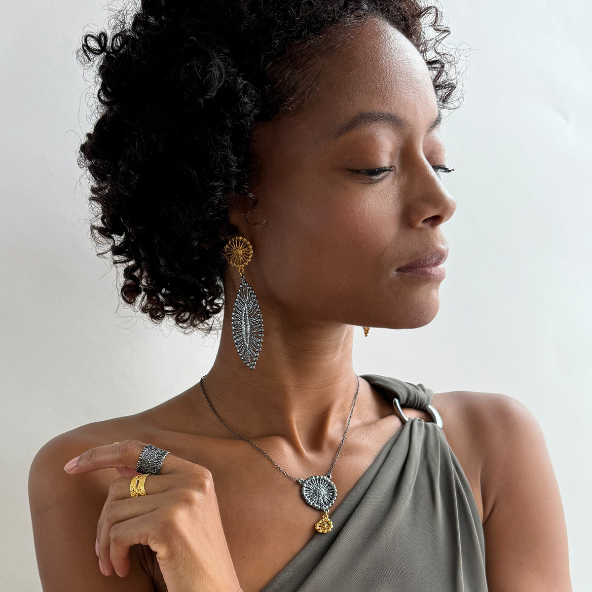 A model wearing a pair of leaf shaped 24k gold and black oxidized sterling silver earrings.