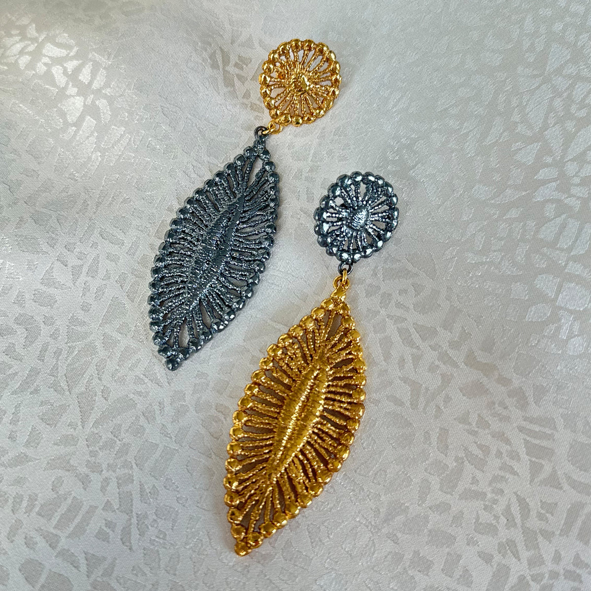 Pair of leaf shaped 24k gold and black oxidized sterling silver earrings.