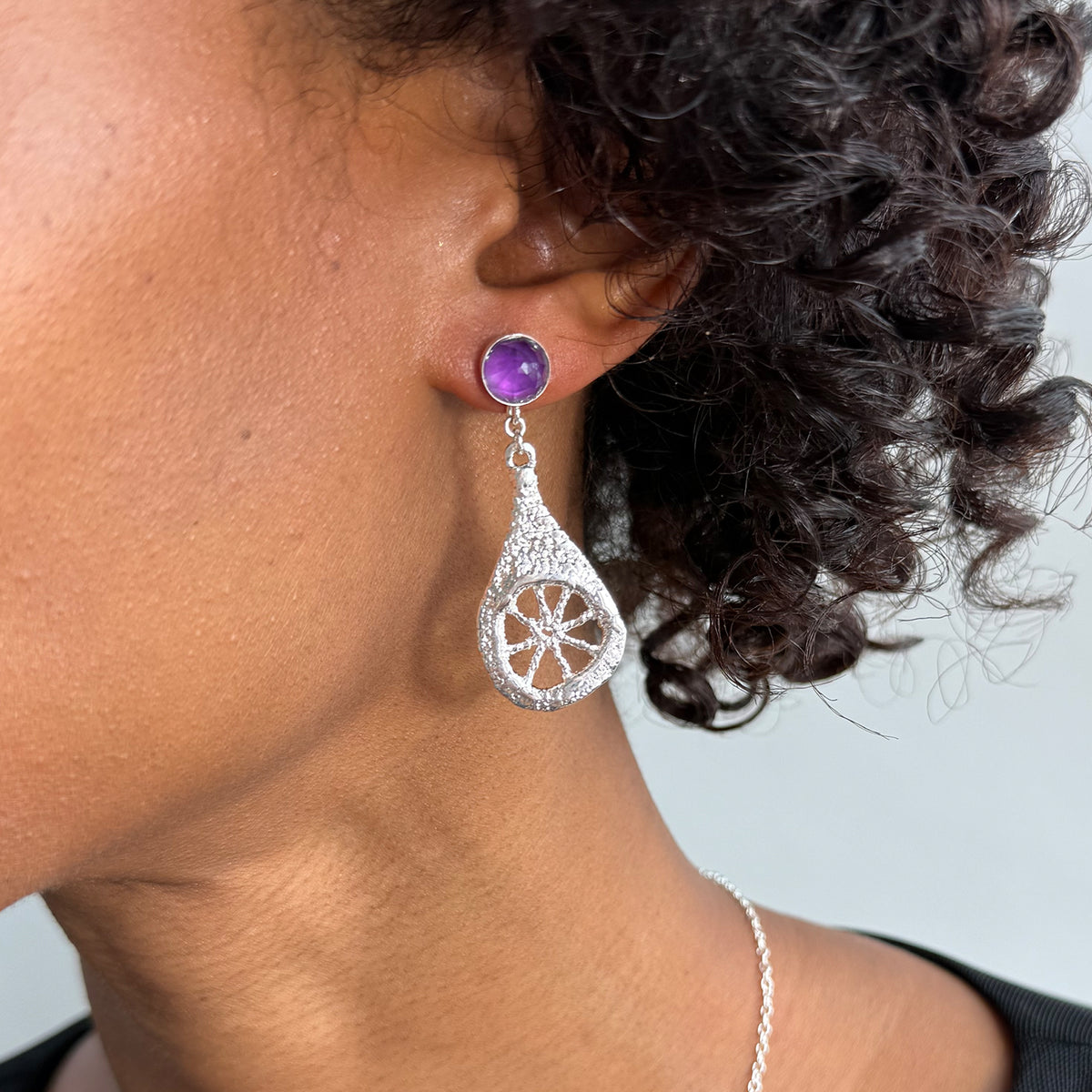 Model wearing lace teardrop earrings in sterling silver with amethysts.