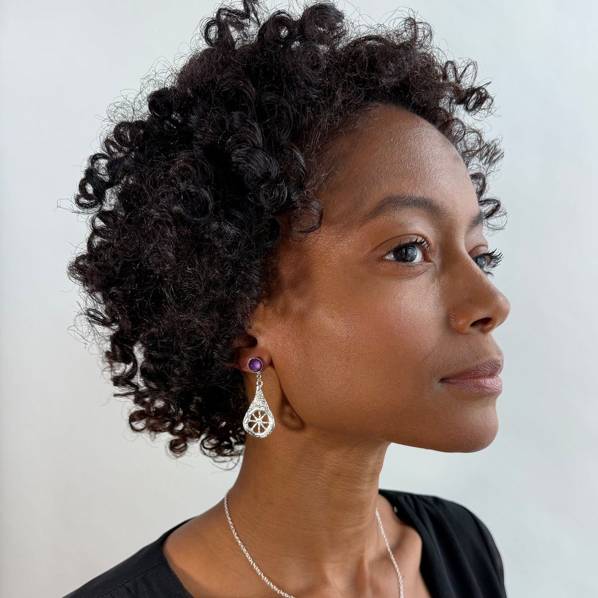 Model wearing lace teardrop earrings in sterling silver with amethysts.
