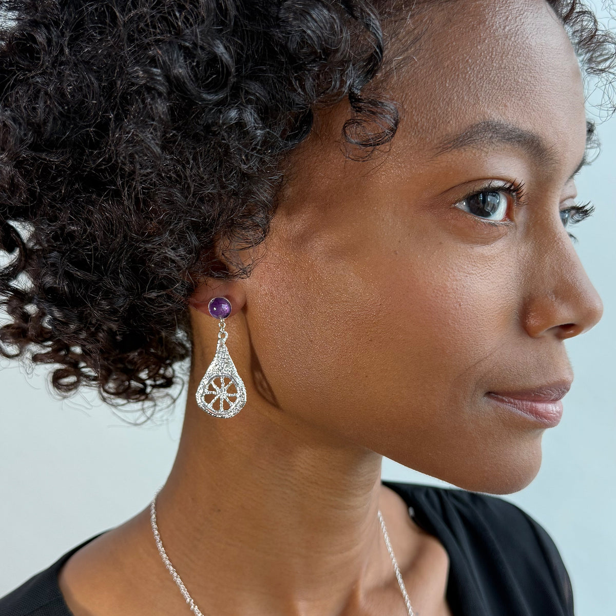 Model wearing lace teardrop earrings in sterling silver with amethysts.